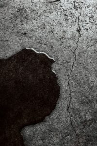 Wet cracked concrete surface showing slab leak water damage spreading beneath a home foundation